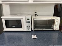 Photo showing both the Sunbeam microwave SGS90701W and Hamilton Beach toaster oven model 31160 placed side by side on countertop.