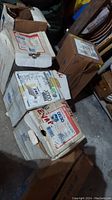 Photo showing six cardboard boxes containing motors, some open, some sealed, placed on a garage floor amid other items.