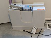 Closed beige hard plastic case containing the Emdko Model 5400 sewing machine.