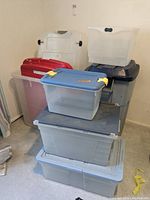 Stacked plastic storage totes of various sizes and colors, showing condition and features