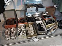 Wide view of all shoes in boxes and on floor showing variety of styles including sneakers, boots, heels, flats.