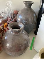 Two gray glazed Canfloyd pottery vases shown side by side with plastic food bags and other items in background