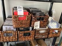 Six woven baskets filled with CDs placed on shelves; visible CD album covers include various artists and genres.