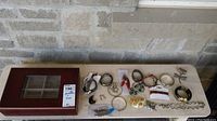 Photo showing wooden jewellery box with glass top and assorted costume jewellery laid out beside it