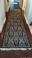 Full view of the black and beige wool runner rug showing overall design and length on hardwood floor.