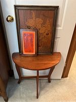 Photo showing the half moon wooden table with two framed art pieces placed on top, against a door.