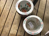 Top-down view showing inside of both ceramic planter pots with koi fish motif and floral borders.