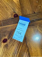 Close-up of the label showing table dimensions and lot info on the knotty pine table surface.