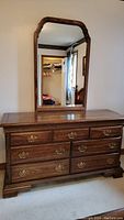 Full frontal view of the wood dresser with mirror against wall.