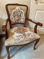 Full view of the wooden carved armchair with embroidered fabric seat and backrest depicting floral and Victorian dancing couple design.