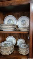 Plates arranged on wooden cabinet shelves showing multiple stacks