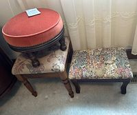 Three foot stools grouped together on light-colored carpet near window. Round rust-colored velvet stool on top of floral rectangular stool, taller floral square stool beside them.