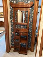 Front view showing the entire hall tree, carved wood frame, central mirror, shelves, drawer, and umbrella stand base.