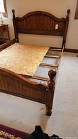 Full side view of queen bed frame showing the headboard and footboard with cannonball finials, wooden slats and particle board base support.