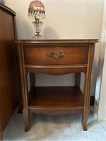 Front view of wooden side table with lamp on top