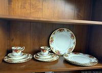 Full view of tea set components with cups, saucers, dessert, luncheon, and dinner plates arranged on shelf