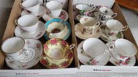 Two cardboard boxes containing twelve assorted teacups and saucers