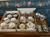 Two cardboard boxes holding the twelve teacups and saucers, plus cream jug, sugar bowl and teaspoon box on side table