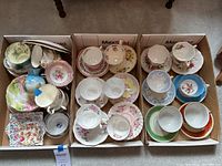 Three cardboard boxes containing assorted teacups, saucers and plates