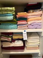 Full view of two shelves filled with a variety of bath and hand towels in multiple pastel and dark colors.