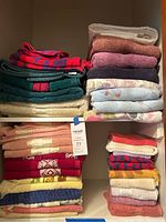 Two shelves with bath and hand towels in various colors and sizes folded and stacked.