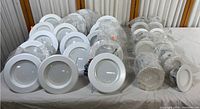 Thirty total LED can retrofit lights arranged on a table, including round white trims and wrapped lamps.