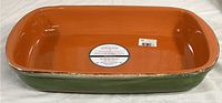 Top view of rectangular ceramic baking dish showing orange interior glaze and green exterior with rim detail