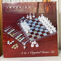 Front of box showing the Imperial Crystal 3-in-1 game set with chess pieces, checkers/backgammon pieces, dice, and crystal game boards.