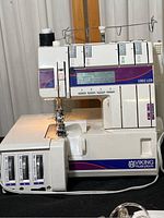 Front view of Husqvarna Viking 1002 LCD sewing machine with LCD screen, dials, and spool holder visible.