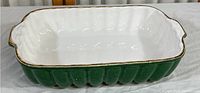 Side view of the green ceramic baking dish showing gold rim and ribbed exterior texture.
