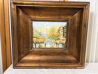 Full view of the deep wooden frame with the embedded small oil painting of a Paris street scene.