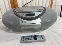 Photo of silver Sony CFD-S350 boombox and remote control on white surface, front and top view showing speakers, display, and control buttons.