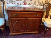 Front of wooden server with closed cabinet doors and drawer with brass handles