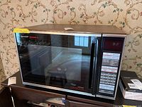 Front view of Sharp Carousel II microwave convection oven showing black glass door and stainless frame with controls on the right side.