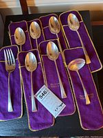 Eight sterling silver serving pieces on purple velvet sleeves