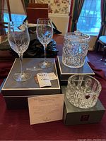 Overview of two wine glasses, lidded canister, bottle coaster and original boxes on table