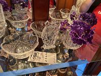Full set on glass shelf including two crystal bowls, crystal vase with faux purple flowers, and crystal harp figurine