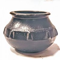 Front view of small round bronze mortar showing decorative ridges around body and slight patina.