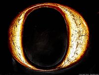 Front view of the heavy cast iron letter 'O' with burnished gold paint, showing textured surface and vintage patina.