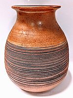 Front view of the rounded mid century vase showing the brown orange textured glaze and black and white horizontal stripes.