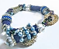 Close-up of vintage bracelet featuring blue, silver, and purple beadwork with clustered pearls and rhinestones.