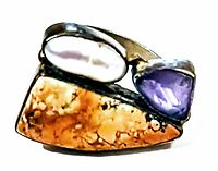 Top view of the vintage ring displaying the mother of pearl oval, rectangular marbled stone, and amethyst teardrop.