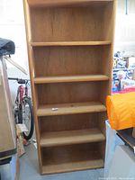 Full frontal view of oak veneer bookcase standing among other stored items.