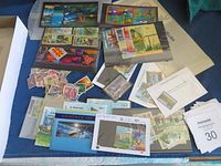 Wide shot showing multiple batches of stamps including souvenir sheets, loose stamps, and envelopes respectively