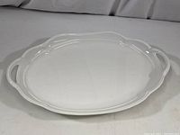 White oval ceramic serving platter shown flat with handles visible, highlighting shape and size.