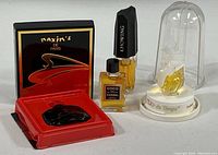 Four perfume bottles shown together: Coco Chanel, Maxims de Paris, L'Air du Temps in display dome, Estee Lauder Knowing