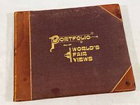 Closed front cover of the portfolio book 'Portfolio of World's Fair Views' showing brown textured cover with leather corners and spine and gold embossed title.