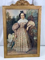 Full view of vintage framed print showing Victorian woman in floral dress with puffed sleeves, gold-painted wooden frame with top carved flourish.