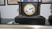 Vintage Ansonia mantle clock showing full front view with black body and gold bezel.