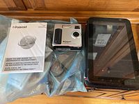 Photo showing Polaroid PDC 3030 digital camera with user manuals and Samsung Galaxy Tab tablet, front view.